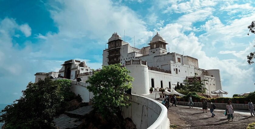 The verdant greenery surrounding the Sajjangarh Fort with people during the daytime.