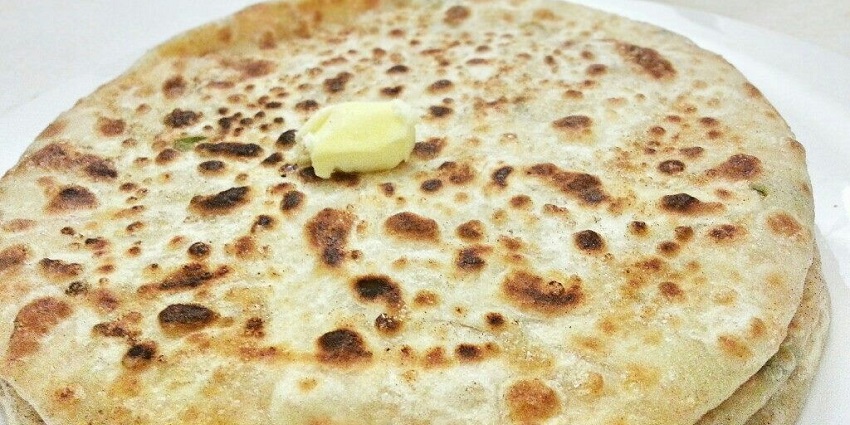 Flatbread stuffed with spiced radish filling, served with butter, chutney, and yogurt.