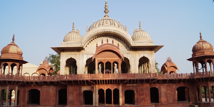 A stunning cenotaph with intricate carvings and a serene water body, reflecting Rajput and Mughal architecture.
