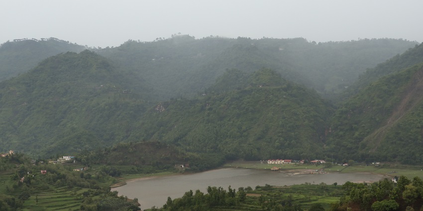 The view from the hills covered with the lush green forest and the beautiful pond in between