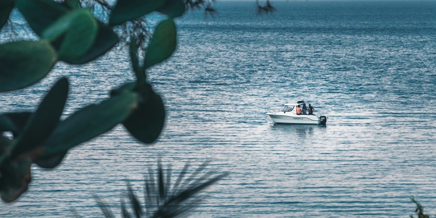 Image of a lake with clear water and people on a motorboat during day time