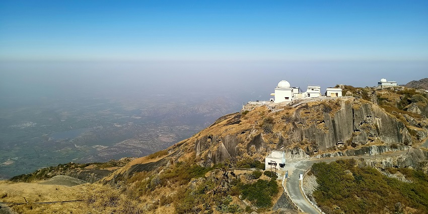 An image of a peaceful white concrete building on top of a mountain during the day.
