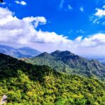 A scenic view of a mountain in Mount Abu, featuring rocky terrain and green vegetation.