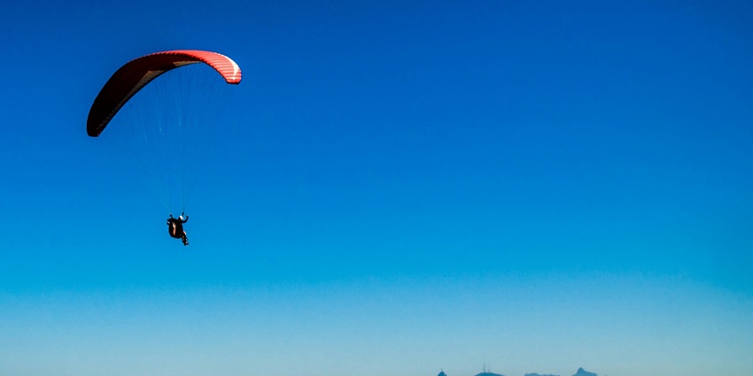Thrilling paragliding experience under a clear blue sky at Mountain Adventure Park.