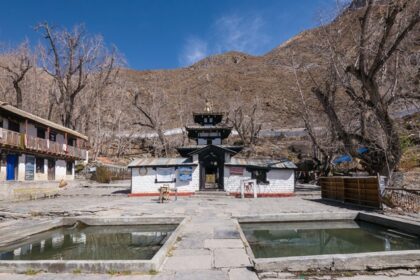 The Muktinath Temple in Nepal with mountains in the background and brown trees.