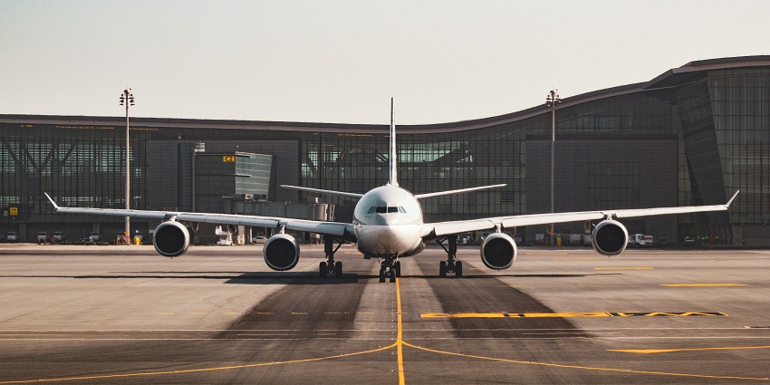 A view of Mundra Airport runway with a plane in the background and industrial landscape.