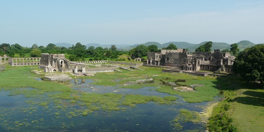 Scenic Munja Talao lake surrounded by ancient structures and serene natural beauty.