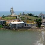 An aerial view of a majestic statue of Shiva surrounded by azure waters and golden sands.