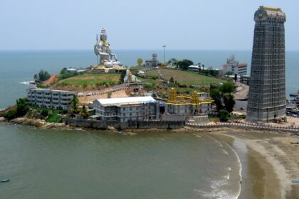 An aerial view of a majestic statue of Shiva surrounded by azure waters and golden sands.