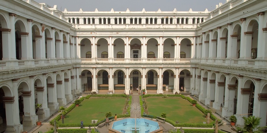 A hallway in an art museum and the open courtyard with the beautiful fountain in the middle of it.