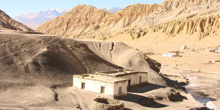A picture of a deserted hill with the ruins of houses and monuments in the middle on a sunny day