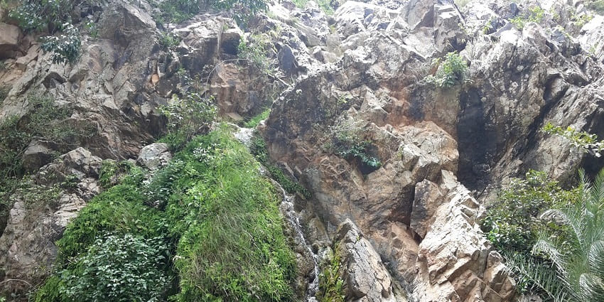 Muthyala Maduvu Waterfalls, surrounded by lush vegetation and stony landscape.