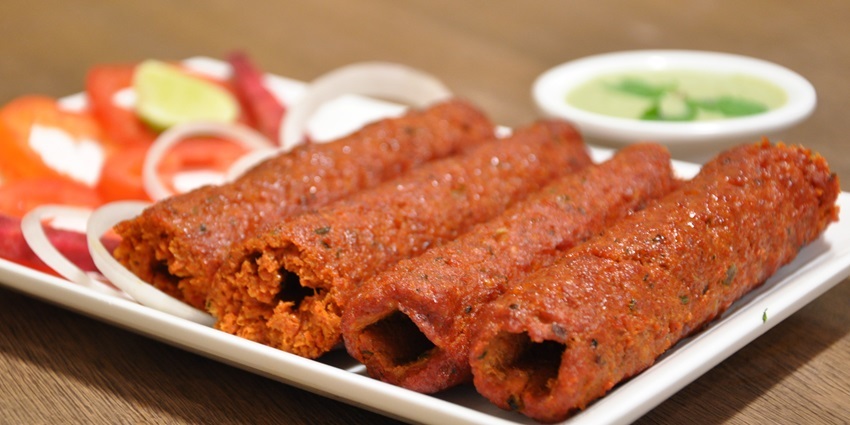 Mutton seekh kabab served with mint chutney, onions, lemon and tomatoes