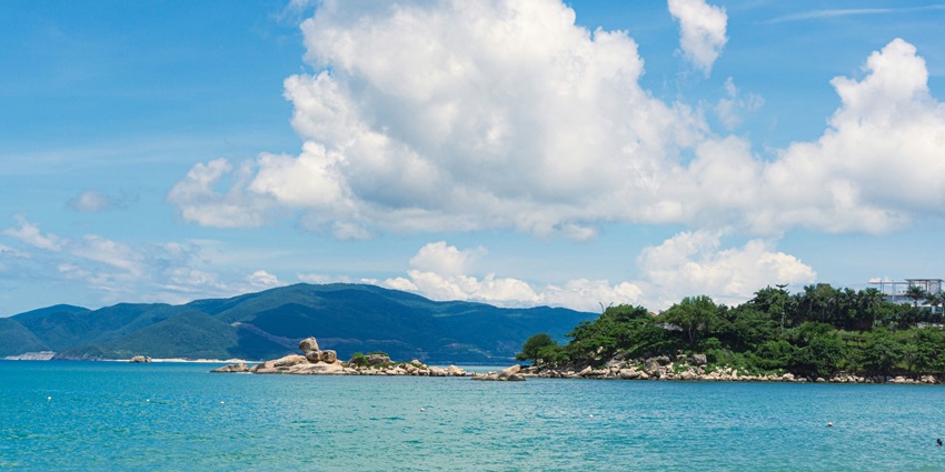 Nha Trang Beach features an expansive sandy coastline, gentle waves, and distant boats.