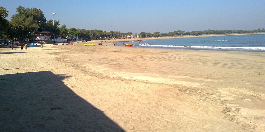 Scenic view of Nagoa Beach with golden sands and gentle waves under a clear blue sky.