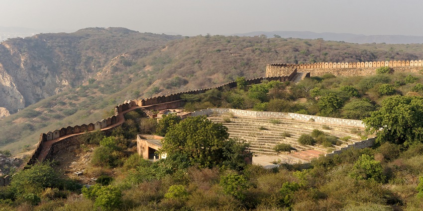 An aerial view of the Nahargarh Fort nestled in the peaks and surrounded by greenery.
