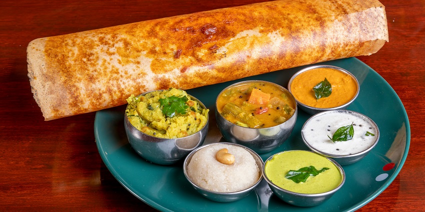 A mouth-watering view of a plate served with dosa and cooked vegetables on the side.