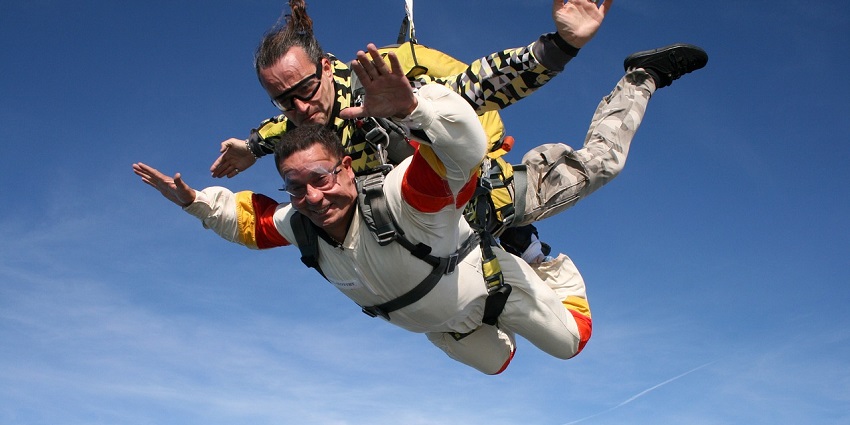 Two men skydiving in Pattaya, wearing skydiving wear and hanging from the parachute.