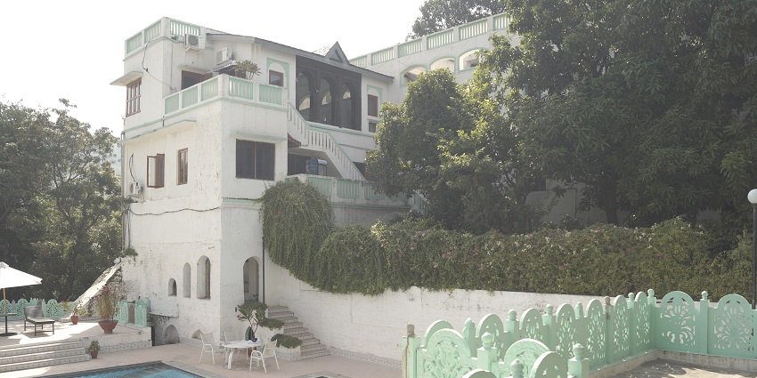 The Palace of Nalagarh, with pastel accents, a pool, and lush greenery all around.