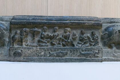 A stone panel with carvings for people and animals displayed in Nalanda Museum.