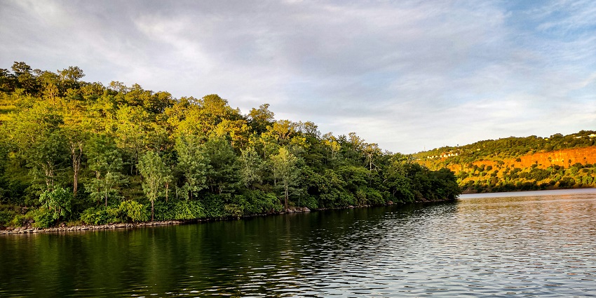 A serene lake surrounded by hills in the Nallamala Hills region, reflecting the clear sky and lush vegetation