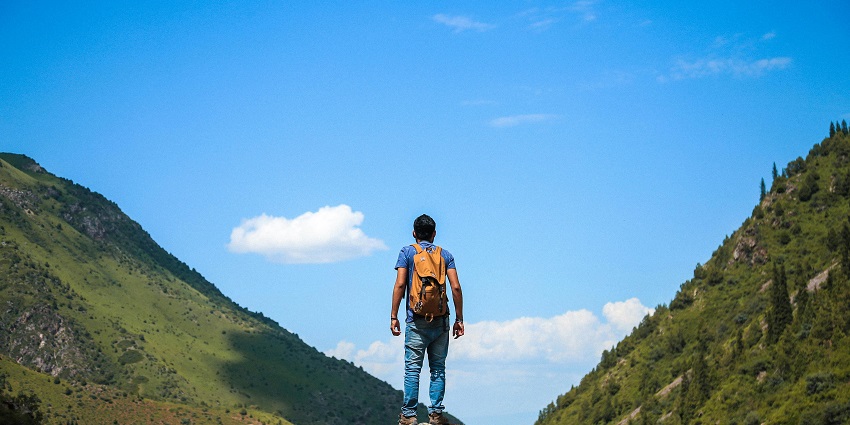 Image of a man standing on a rock - Nandeshwar Ji Temple offers serene trekking in lush, rocky Aravalli Hills