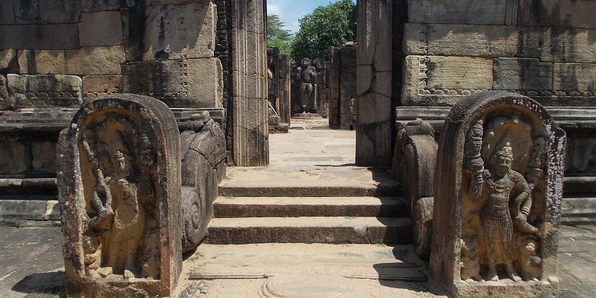 Ancient stone ruins with weathered structures and greenery, showcasing historical architecture