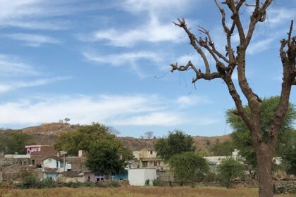 A glimpse of a village surrounded by majestic peaks and lush greenery in Rajasthan.