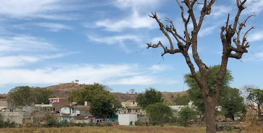 A glimpse of a village surrounded by majestic peaks and lush greenery in Rajasthan.