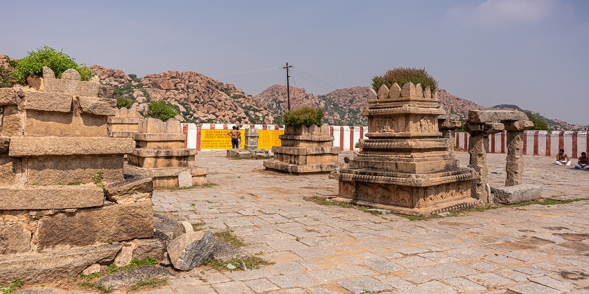 Navabrindavana island and temple. 5 brown stone monuments for saints under blue sky with some green foliage