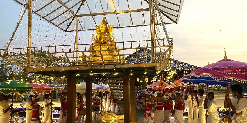 A breathtaking view of a temple with a golden idol of god on top and people on the side.