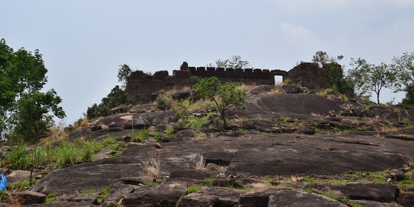 A picture of the ruins of a fort in Kerala, surrounded by trees and greenery