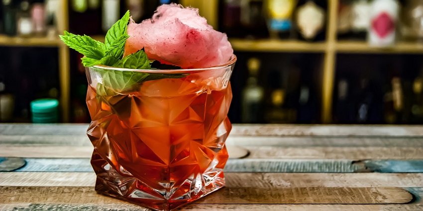 A vibrant Negroni cocktail in a glass, garnished with an orange slice and ice cubes.