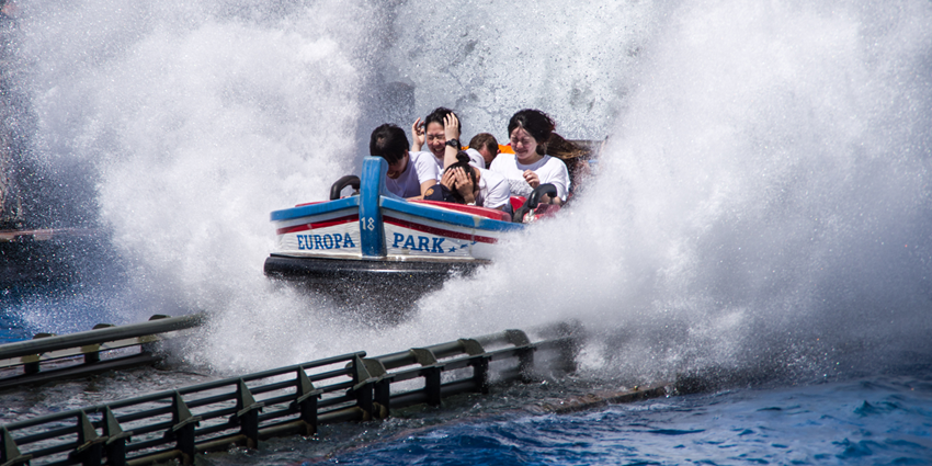 Poseidon water coaster ride at Europa Park with Greek-themed architecture in the background.
