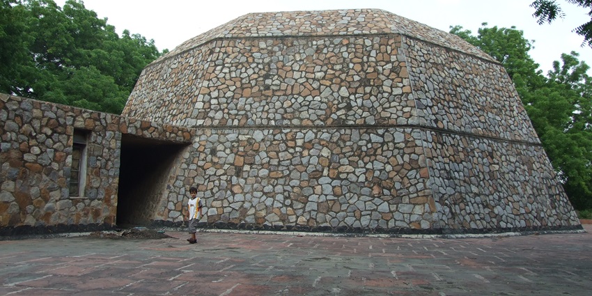 A picture of a sizable structure at the Nehru Planetarium surrounded by greenery and trees