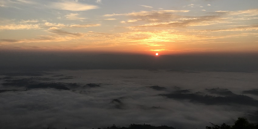 Sunrise at Netarhat View Point, with the golden sun casting a warm glow over the misty valleys below