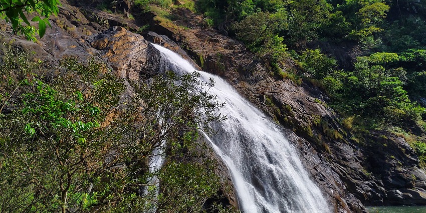 Netravali Waterfall cascades down rocky cliffs, surrounded by lush greenery
