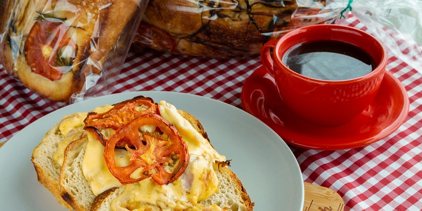 A mouth-watering view of a plate served with scrambled eggs and a slice of tomato.