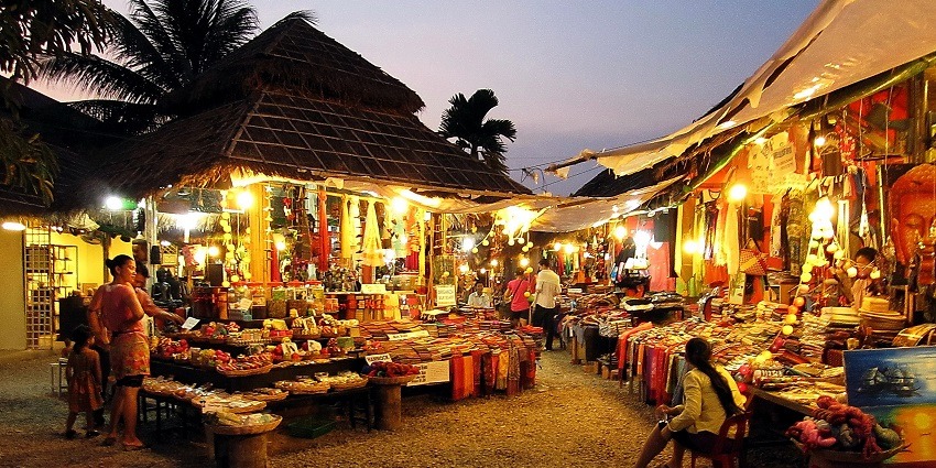 A vibrant night market bustling with colorful stalls and lively crowds under twinkling lights.