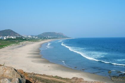 Image of serene beach view with high buildings surrounding and rocks on the seashore