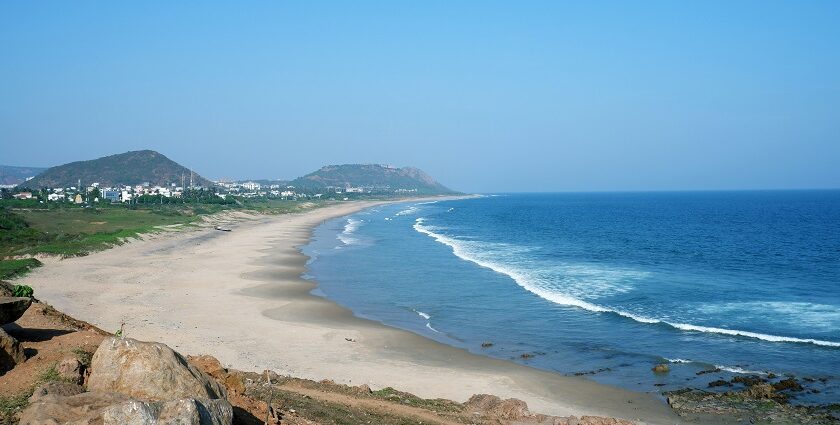 Image of serene beach view with high buildings surrounding and rocks on the seashore