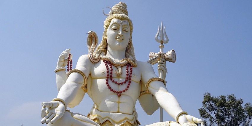 Large statue of Lord Shiva, a Hindu deity, prominently displayed outdoors during the day.