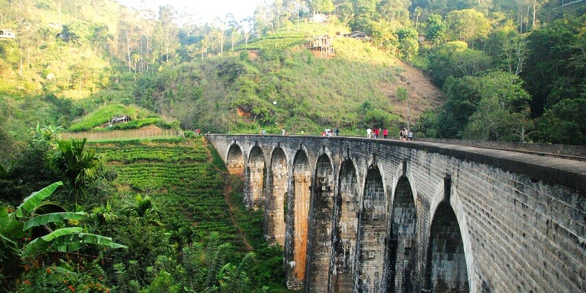 Nine Arches Bridge with its iconic stone arches spanning a lush green valley and forest