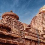 An image of a majestic ancient stone temple in Odisha under a clear blue sky.