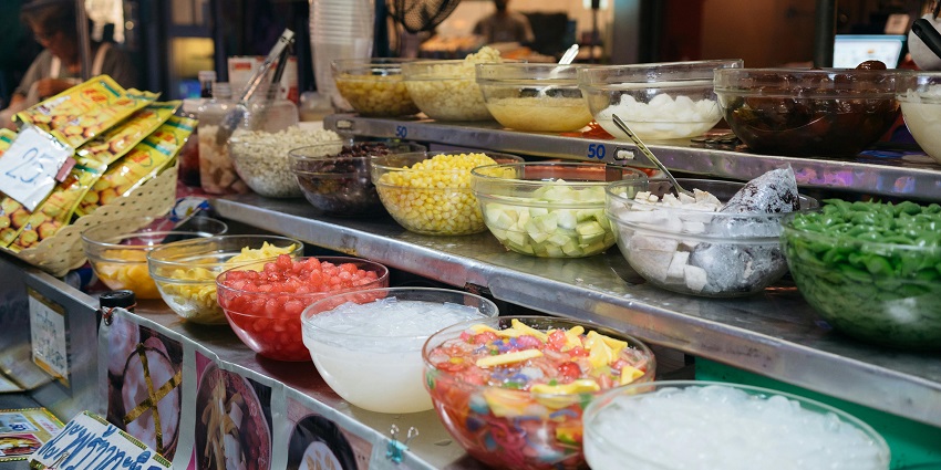 A display of various food items of different colours kept in a glass bowl on steps.
