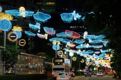 A car driving down a street covered in Christmas lights at Orchard Road in Singapore.