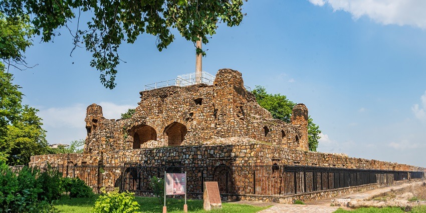 A frontal view of a fort in Delhi with a garden on both sides of its walkway