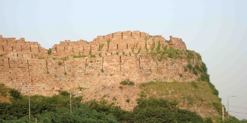 A picture of the outer walls of the Tughlaqabad Fort surrounded by forest in the Aravali Hills
