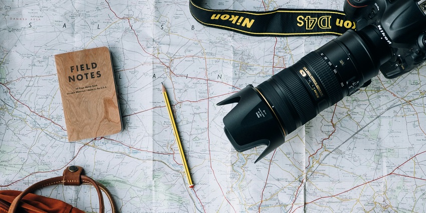 A flat lay of a camera, a book, and a bag arranged aesthetically on a surface.