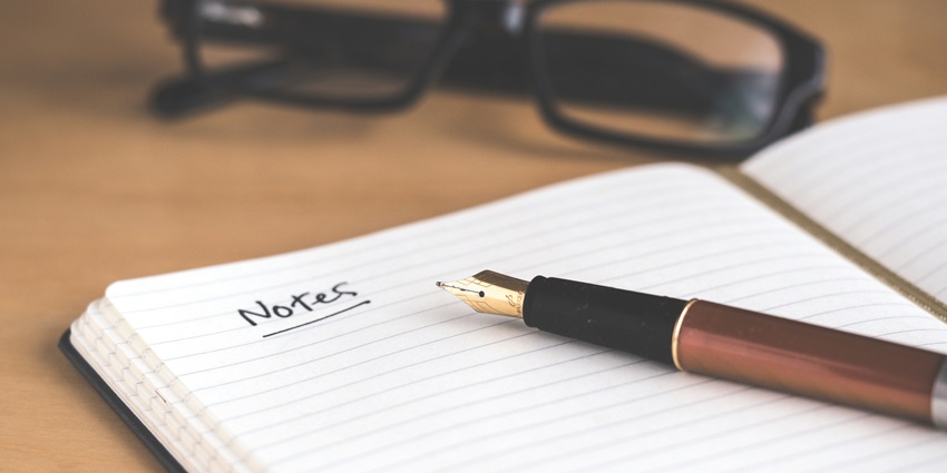 A stunning selectively focused view of a brown fountain pen sitting on a white notebook.